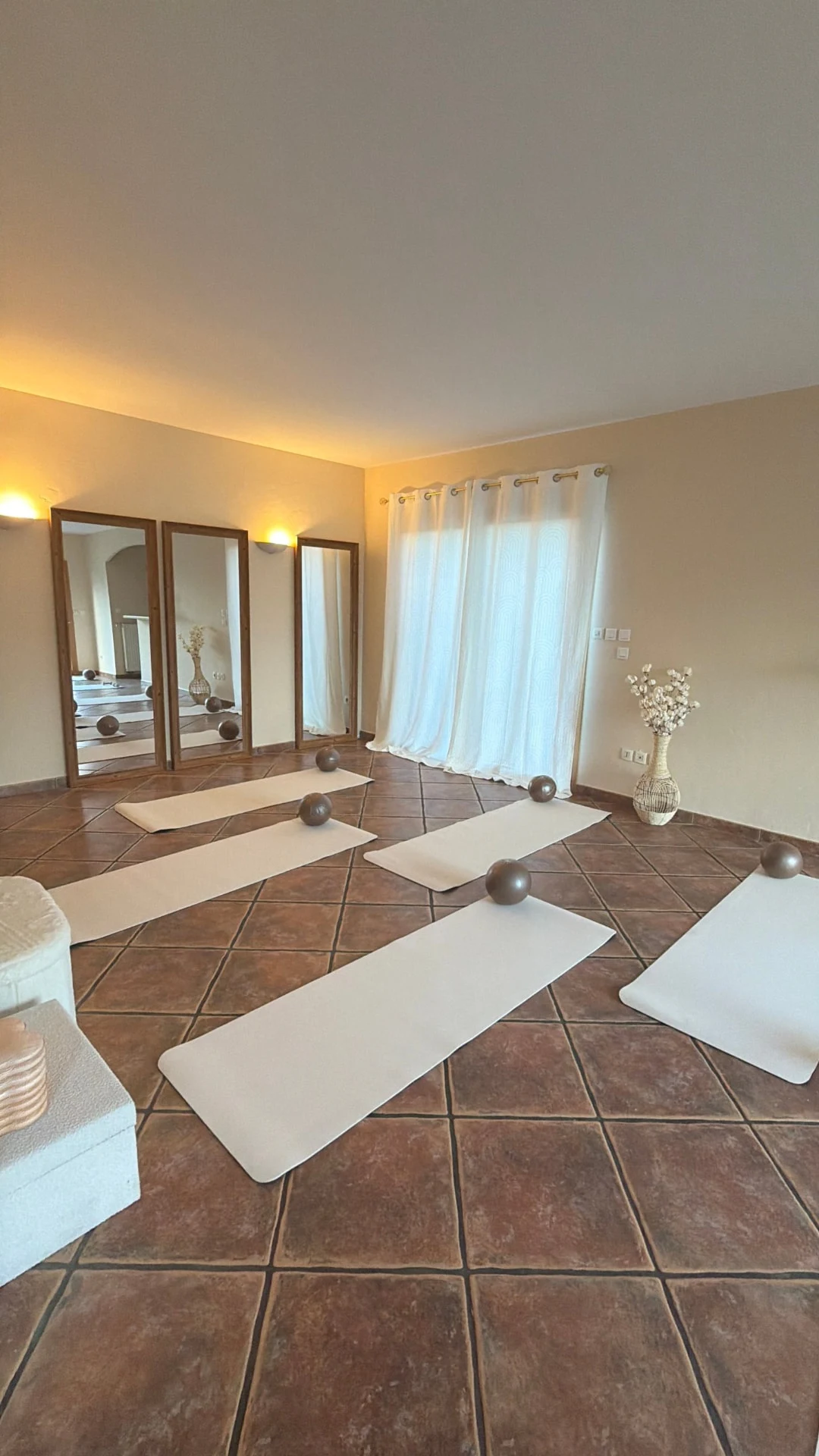 Tapis et ballons disposés face aux grands miroirs et aux rideaux du studio