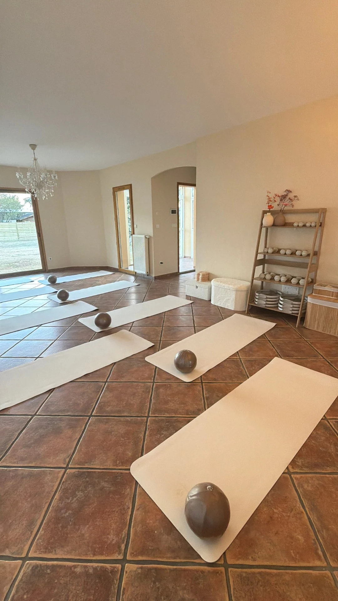 Salle lumineuse avec tapis, ballons et étagère de petit matériel de Pilates